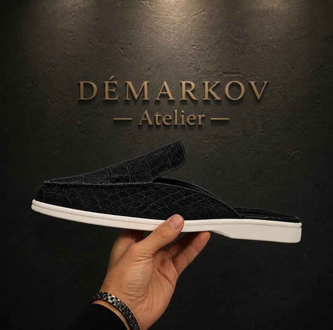 Schwarze Mule im Profil vor der DÉMARKOV Logo-Wand